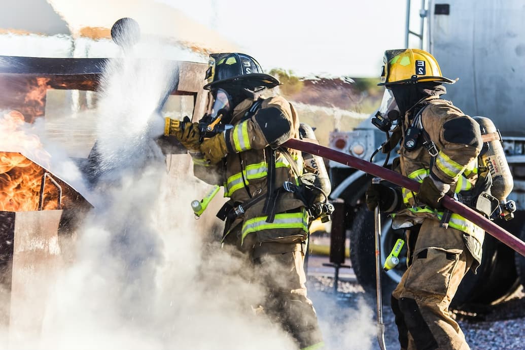 Two firefighters silhouetted against a live training burn