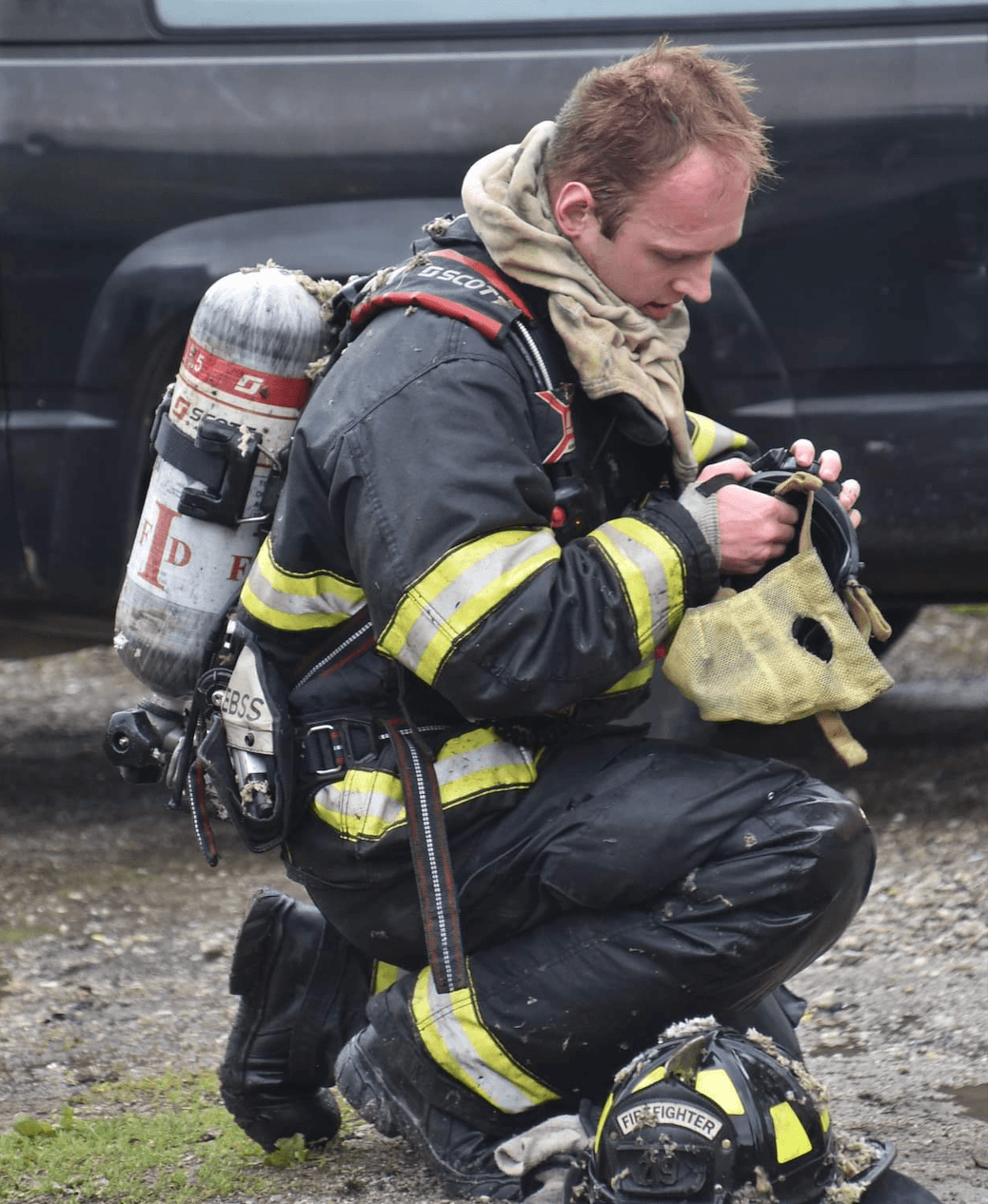 Scott Shimala in turnout gear and an SCBA, kneeling with his facepiece